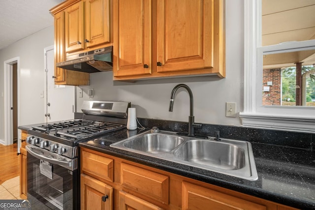 kitchen with hardwood / wood-style floors, gas stove, dark stone counters, and sink