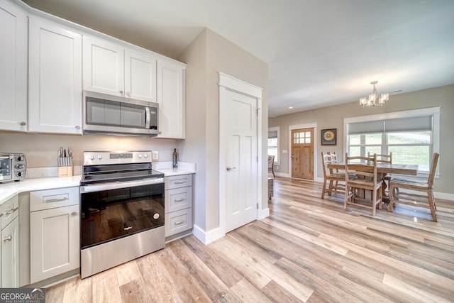 kitchen featuring a wealth of natural light, white cabinetry, light wood-type flooring, and appliances with stainless steel finishes