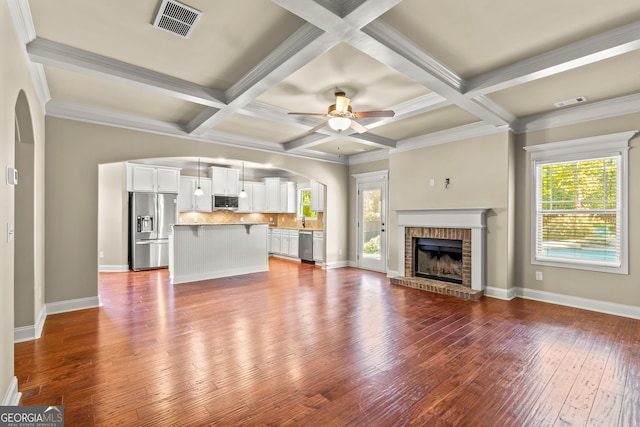 unfurnished living room featuring a wealth of natural light, a fireplace, ceiling fan, and hardwood / wood-style flooring