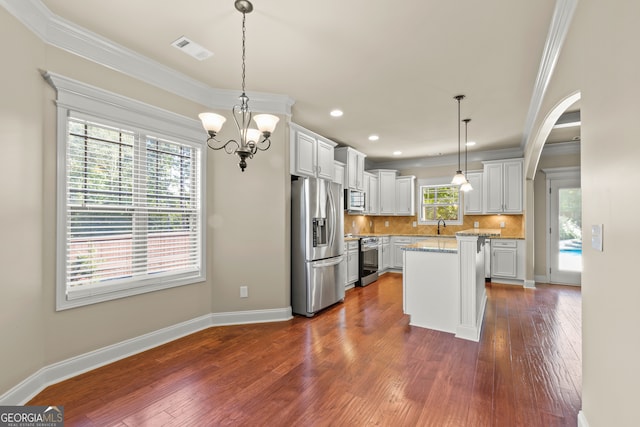 kitchen with white cabinets, dark hardwood / wood-style flooring, pendant lighting, a kitchen island, and appliances with stainless steel finishes