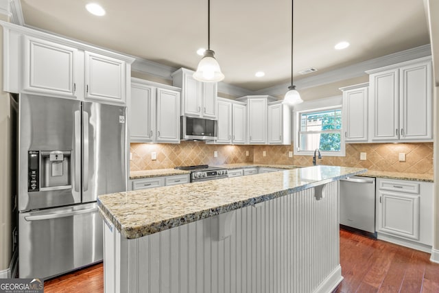 kitchen featuring white cabinets, appliances with stainless steel finishes, decorative light fixtures, and a kitchen island