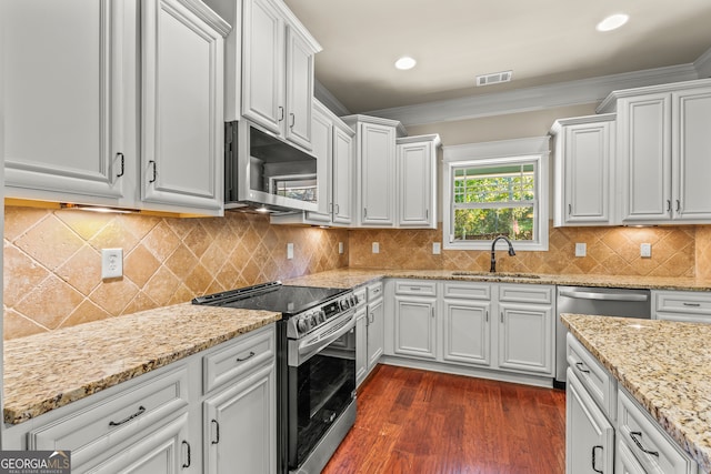 kitchen with backsplash, ornamental molding, stainless steel appliances, sink, and white cabinets