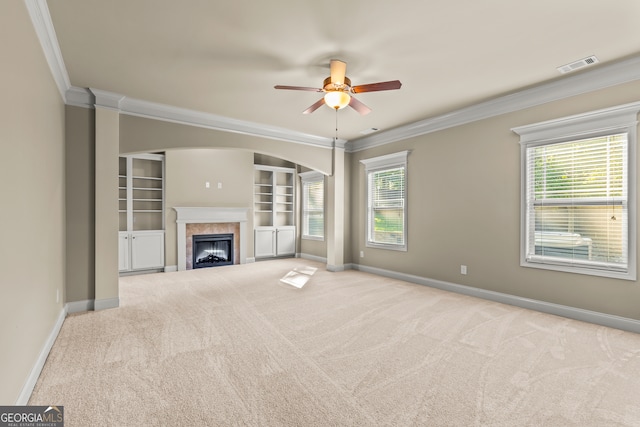 unfurnished living room with ceiling fan, ornamental molding, light carpet, and a tiled fireplace