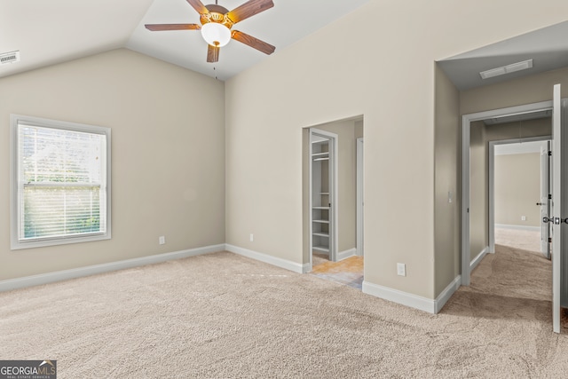 empty room featuring light colored carpet, vaulted ceiling, and ceiling fan