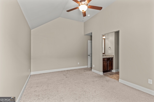 interior space featuring connected bathroom, light colored carpet, vaulted ceiling, and ceiling fan