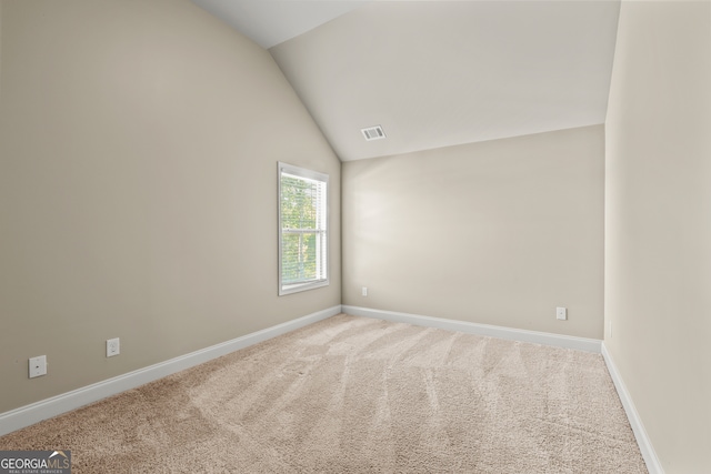 carpeted empty room with lofted ceiling