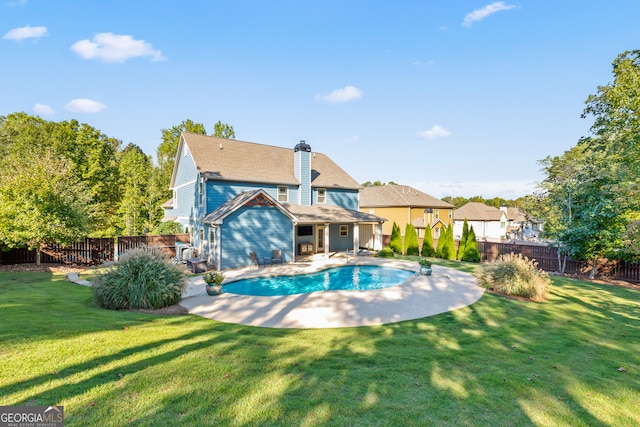 rear view of property with a yard, a fenced in pool, and a patio area