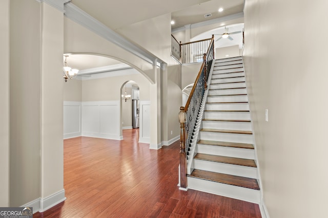 staircase with hardwood / wood-style floors, ceiling fan, and ornamental molding