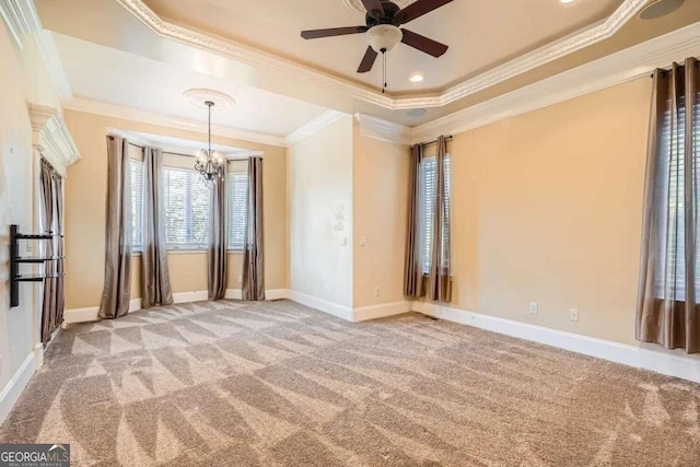 carpeted empty room featuring ceiling fan with notable chandelier, a raised ceiling, and ornamental molding