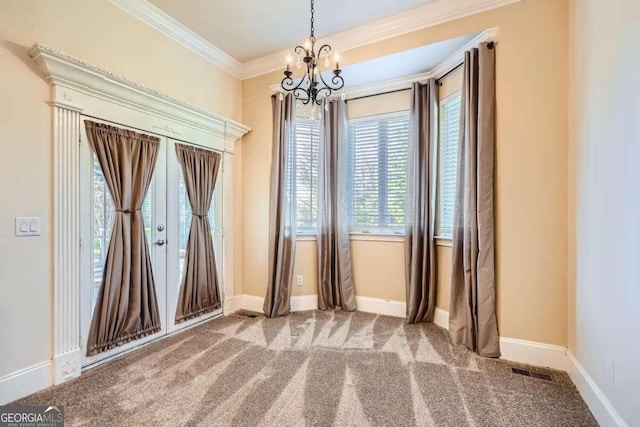 carpeted spare room featuring ornamental molding and an inviting chandelier