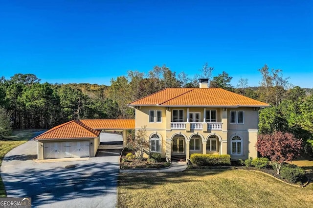 mediterranean / spanish house featuring a balcony, a garage, and a front lawn