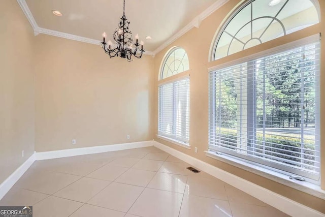 tiled spare room with ornamental molding and a chandelier