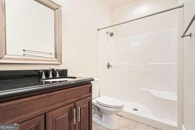 bathroom featuring tile patterned flooring, vanity, toilet, and a tile shower