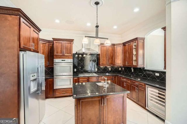 kitchen with appliances with stainless steel finishes, dark stone counters, a kitchen island with sink, decorative light fixtures, and wine cooler