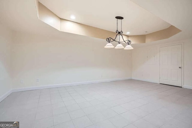 spare room with a raised ceiling and light tile patterned floors