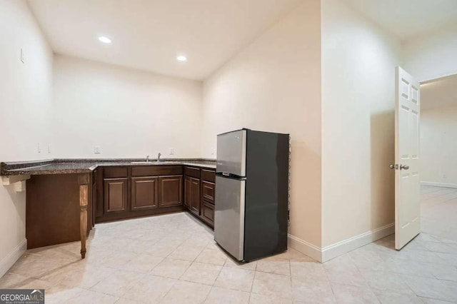 kitchen featuring dark brown cabinetry, sink, and stainless steel refrigerator