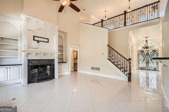 unfurnished living room with tile patterned flooring, ceiling fan, built in features, and a high ceiling