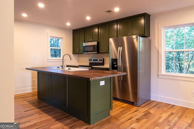 kitchen featuring appliances with stainless steel finishes, light hardwood / wood-style flooring, a kitchen island with sink, and sink