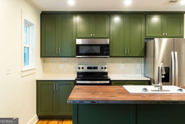 kitchen featuring decorative backsplash, light hardwood / wood-style flooring, stainless steel appliances, and green cabinetry