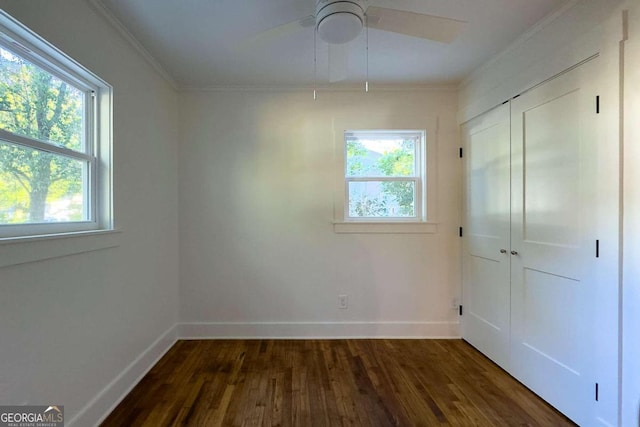 unfurnished room with crown molding, dark wood-type flooring, ceiling fan, and a healthy amount of sunlight