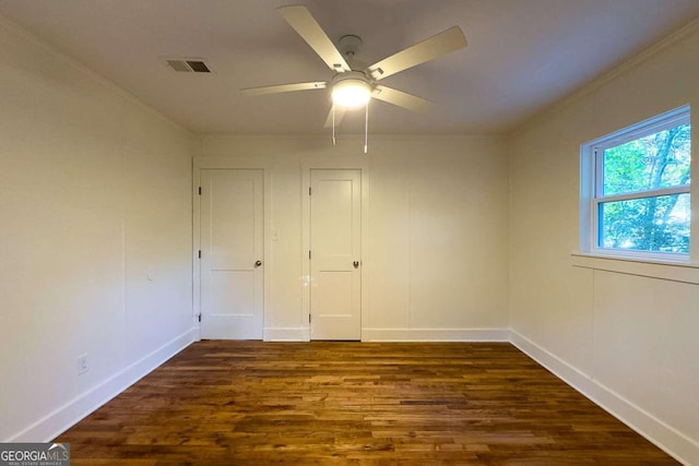 unfurnished bedroom featuring ceiling fan, crown molding, and dark wood-type flooring