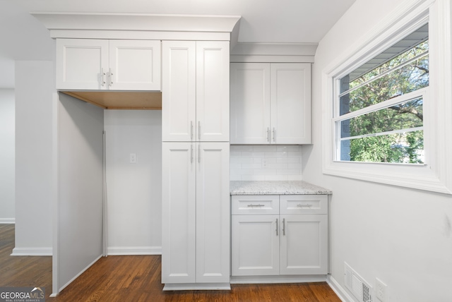 kitchen featuring dark hardwood / wood-style flooring, white cabinetry, light stone counters, and tasteful backsplash