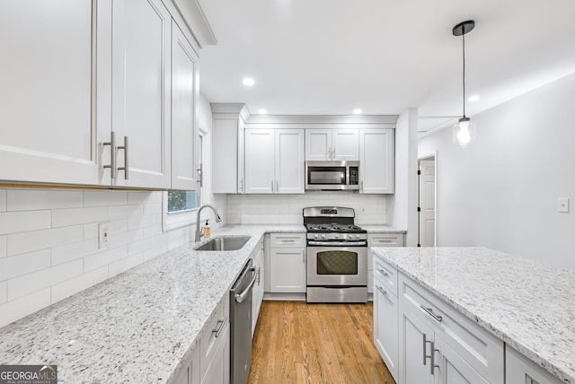 kitchen with sink, hanging light fixtures, light hardwood / wood-style floors, white cabinetry, and stainless steel appliances