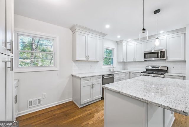 kitchen featuring pendant lighting, dark hardwood / wood-style flooring, white cabinetry, and stainless steel appliances