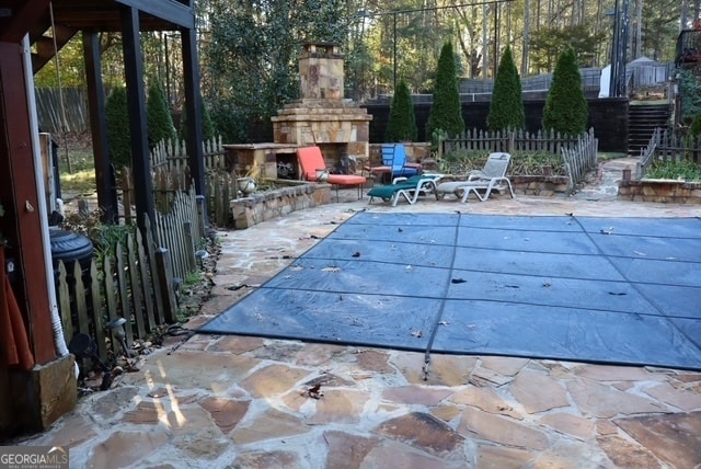 view of swimming pool featuring an outdoor stone fireplace and a patio