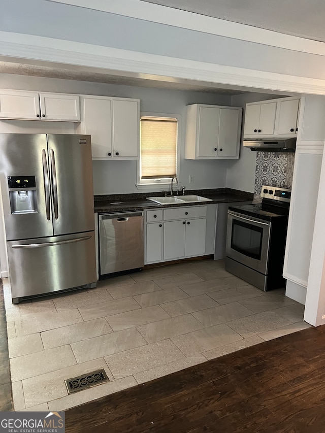 kitchen with appliances with stainless steel finishes, backsplash, sink, white cabinets, and dark hardwood / wood-style floors