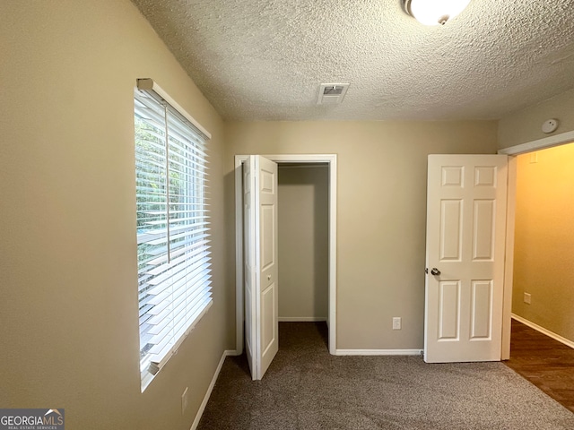 unfurnished bedroom with dark hardwood / wood-style flooring, a textured ceiling, and a closet