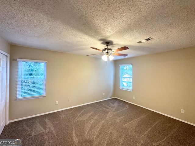 carpeted empty room featuring ceiling fan, a healthy amount of sunlight, and a textured ceiling