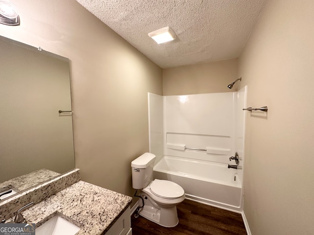 full bathroom featuring vanity, bathtub / shower combination, hardwood / wood-style flooring, toilet, and a textured ceiling