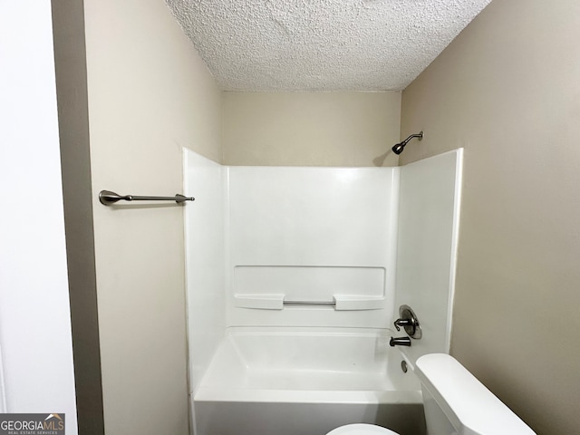 bathroom featuring shower / bathing tub combination, a textured ceiling, and toilet