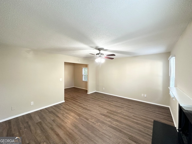 empty room with a textured ceiling, ceiling fan, and dark hardwood / wood-style floors