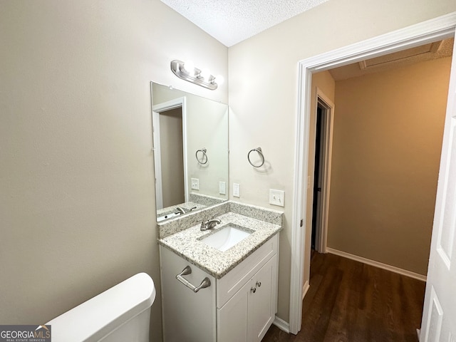 bathroom with vanity, wood-type flooring, a textured ceiling, and toilet