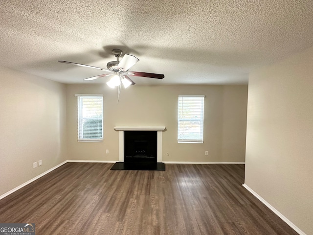 unfurnished living room with a textured ceiling, dark hardwood / wood-style floors, a wealth of natural light, and ceiling fan