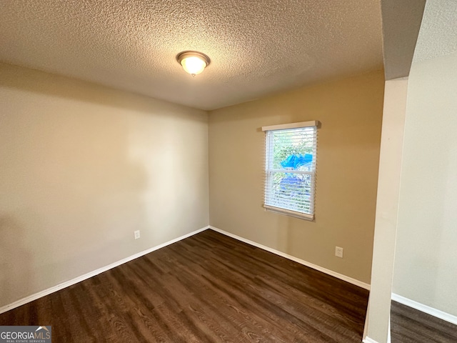 unfurnished room with a textured ceiling and dark hardwood / wood-style floors