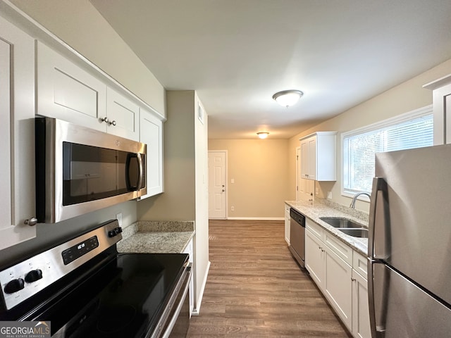 kitchen featuring hardwood / wood-style floors, sink, appliances with stainless steel finishes, light stone counters, and white cabinetry