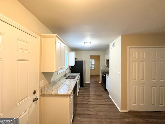 kitchen with sink, dark hardwood / wood-style floors, light stone counters, white cabinetry, and stainless steel appliances