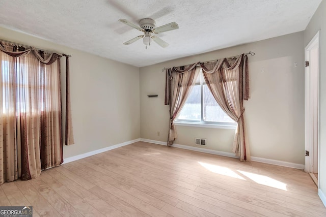 unfurnished room with ceiling fan, a textured ceiling, and light wood-type flooring