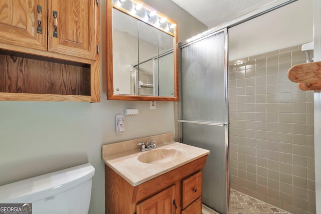 bathroom with vanity, a shower with door, and toilet