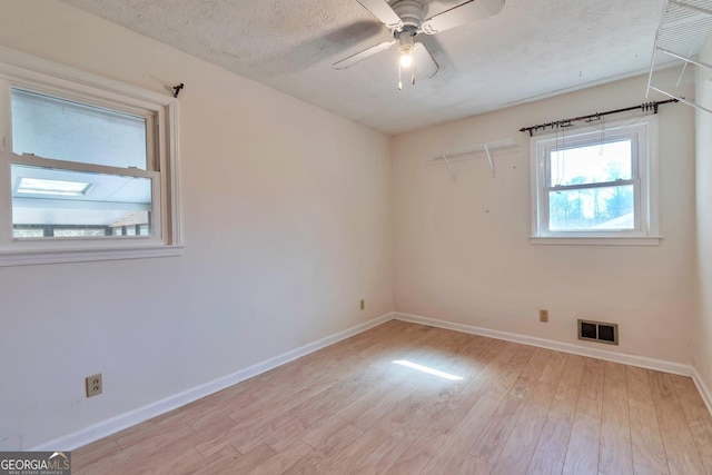 empty room featuring ceiling fan, light hardwood / wood-style flooring, and a textured ceiling