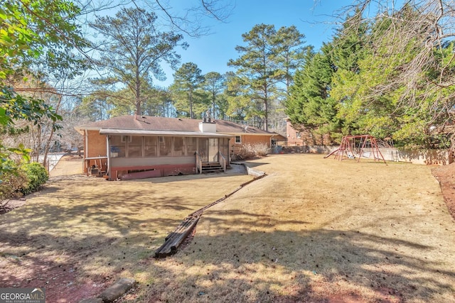 rear view of house with a playground, a sunroom, and a lawn