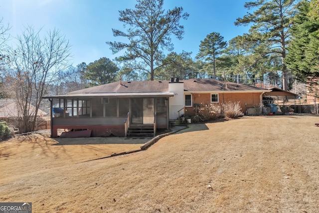 rear view of house with a carport, a sunroom, and a lawn