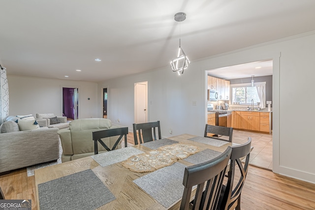 dining area with sink, light hardwood / wood-style flooring, and ornamental molding