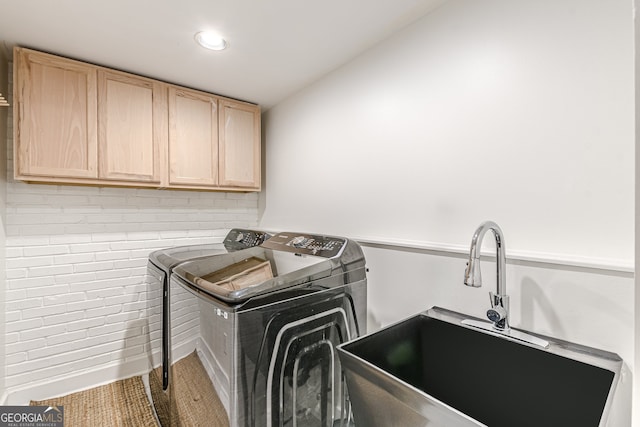 clothes washing area featuring cabinets, sink, and washing machine and clothes dryer