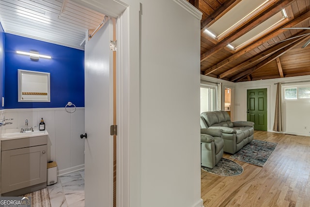 interior space featuring vanity, hardwood / wood-style flooring, lofted ceiling with skylight, and wood ceiling