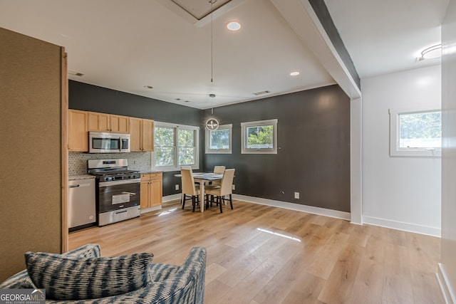 kitchen featuring light brown cabinetry, stainless steel appliances, decorative light fixtures, and light wood-type flooring