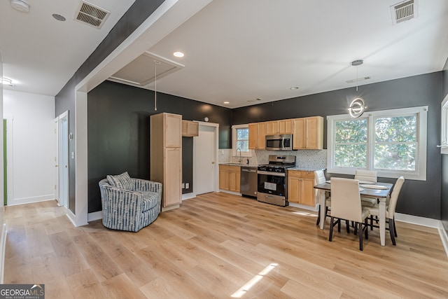 kitchen featuring hanging light fixtures, decorative backsplash, light stone countertops, light wood-type flooring, and appliances with stainless steel finishes